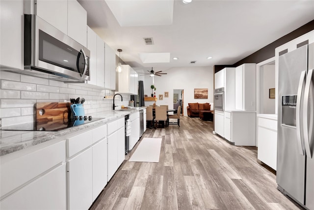 kitchen featuring pendant lighting, white cabinetry, stainless steel appliances, decorative backsplash, and sink