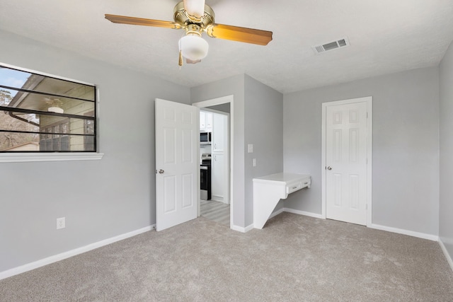 unfurnished bedroom featuring a textured ceiling, light colored carpet, and ceiling fan