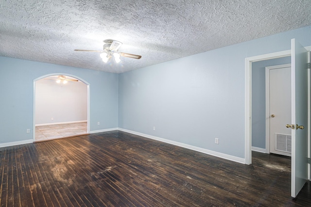 empty room featuring ceiling fan, a textured ceiling, and dark hardwood / wood-style flooring