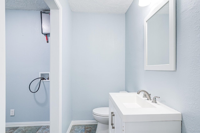 bathroom with vanity, toilet, and a textured ceiling