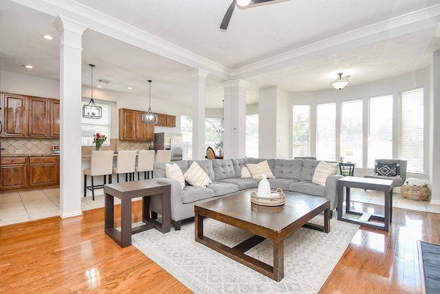 living room featuring ceiling fan, light hardwood / wood-style floors, ornamental molding, and ornate columns