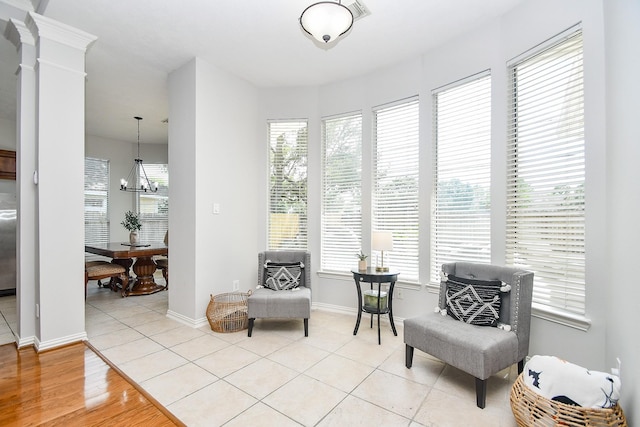 living area featuring light tile patterned flooring, decorative columns, and a chandelier