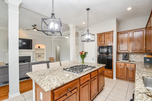 kitchen with black appliances, a center island, light stone counters, and ornamental molding