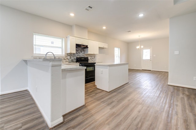 kitchen featuring white cabinets, decorative light fixtures, light hardwood / wood-style flooring, and black electric range