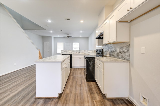 kitchen featuring kitchen peninsula, backsplash, white cabinets, a kitchen island, and black appliances