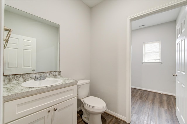 bathroom featuring wood-type flooring, toilet, and vanity