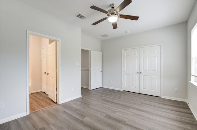 unfurnished bedroom featuring light wood-type flooring, ensuite bathroom, a closet, and ceiling fan