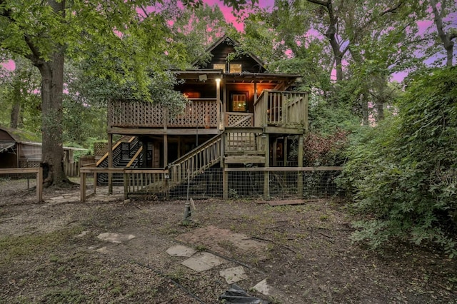 back house at dusk featuring a deck