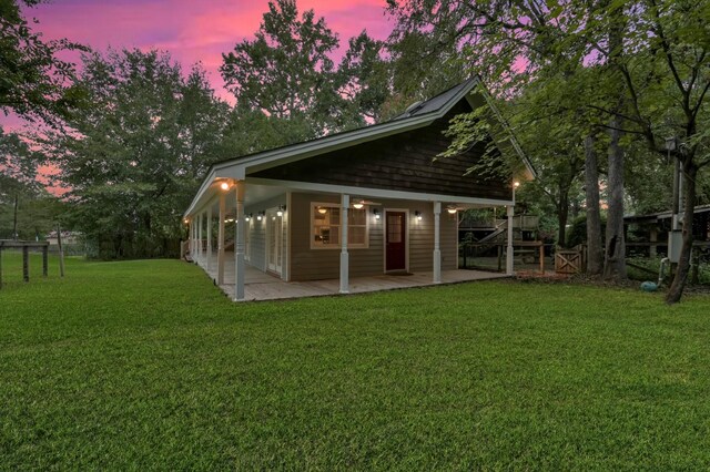 back house at dusk featuring a patio and a yard