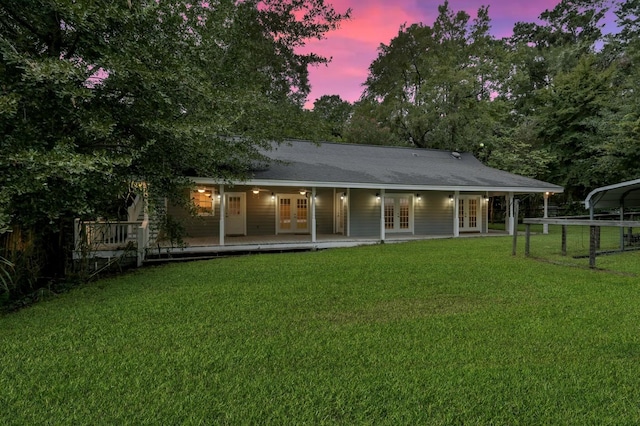 back of house at dusk with french doors, a yard, and a deck