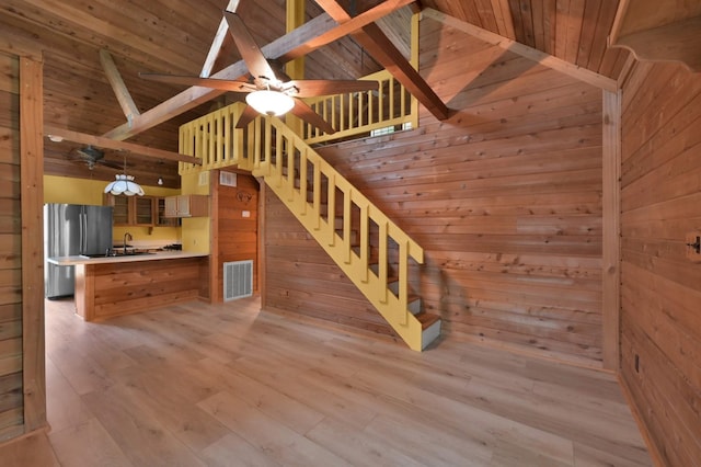 stairway with visible vents, ceiling fan, wooden walls, wood finished floors, and wooden ceiling