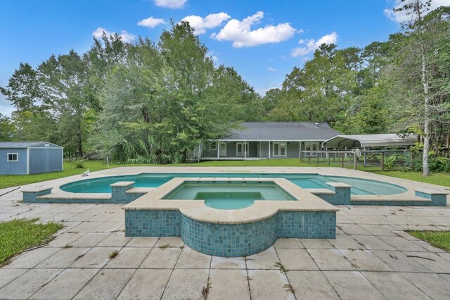 view of pool featuring a lawn, a carport, a storage unit, and an in ground hot tub