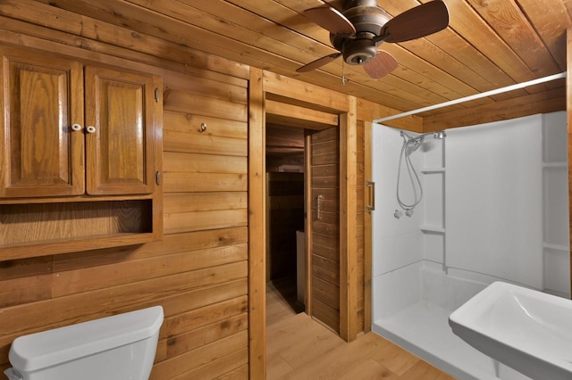 bathroom with walk in shower, toilet, sink, wood ceiling, and wooden walls