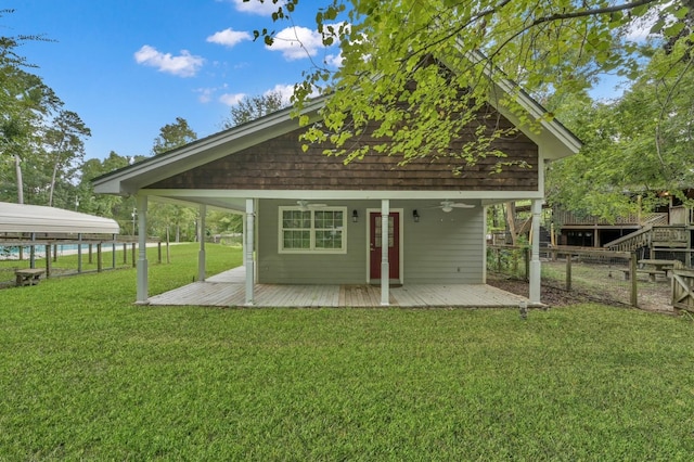 exterior space with fence, a ceiling fan, a lawn, and a wooden deck