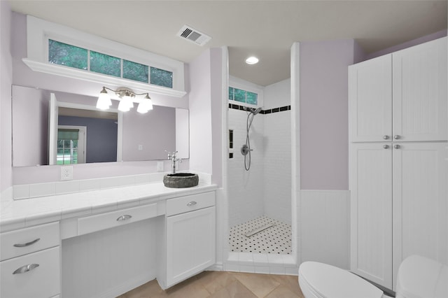 full bathroom featuring visible vents, toilet, tile patterned floors, a tile shower, and vanity