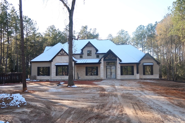 modern inspired farmhouse with metal roof, driveway, a standing seam roof, and stone siding