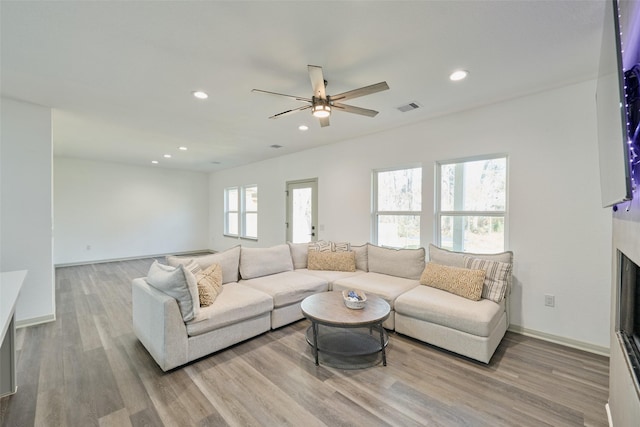 living room with ceiling fan, light hardwood / wood-style floors, and a high end fireplace