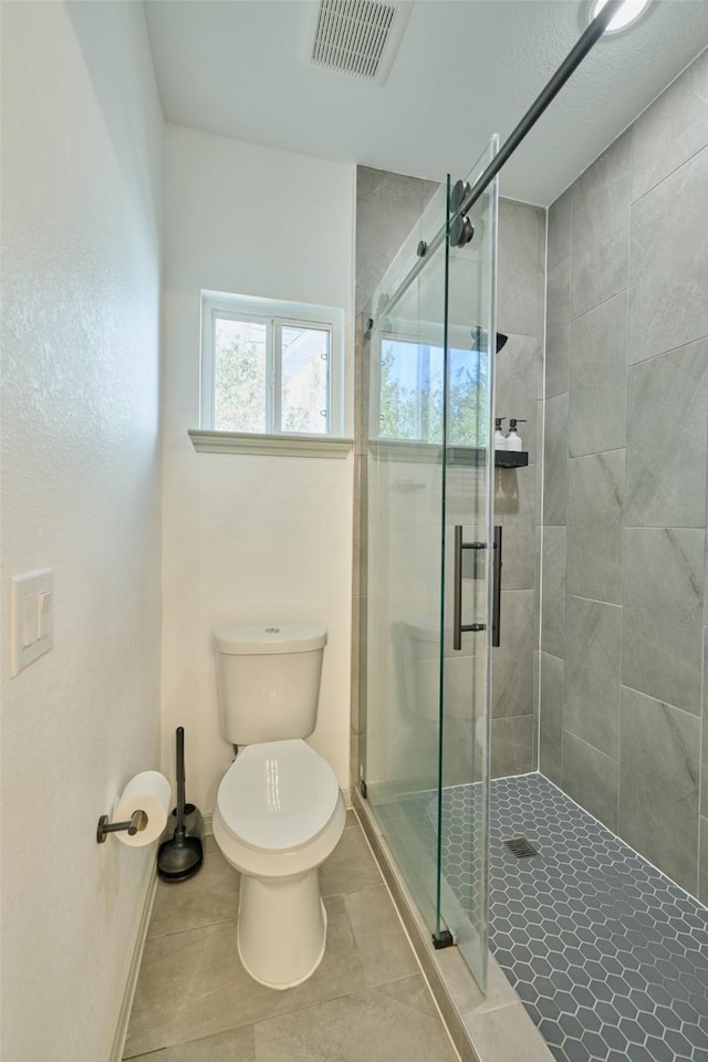 bathroom featuring toilet, an enclosed shower, and tile patterned floors