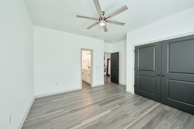 unfurnished bedroom featuring connected bathroom, light hardwood / wood-style flooring, ceiling fan, and a closet