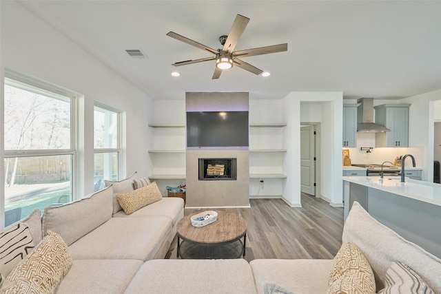 living room with sink, light wood-type flooring, and ceiling fan