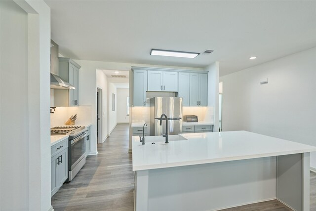 kitchen with sink, stainless steel appliances, light hardwood / wood-style flooring, and wall chimney exhaust hood