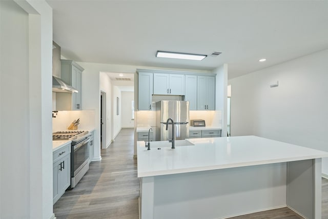 kitchen with sink, backsplash, light wood-type flooring, stainless steel appliances, and wall chimney exhaust hood