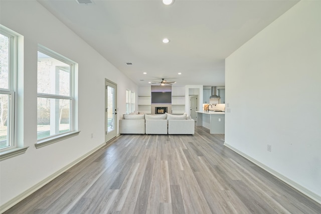 unfurnished living room featuring sink, light wood-type flooring, and ceiling fan