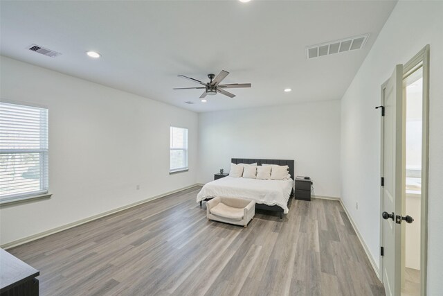 bedroom featuring ceiling fan, ensuite bathroom, and light wood-type flooring