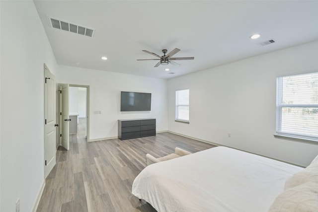 bedroom with ceiling fan, multiple windows, and light hardwood / wood-style flooring