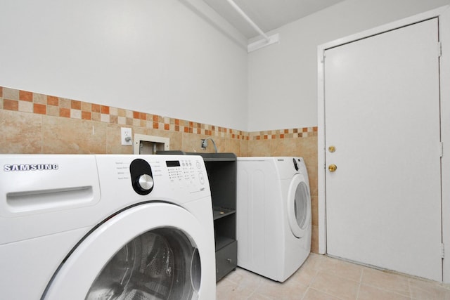 washroom featuring separate washer and dryer, tile walls, and light tile patterned floors