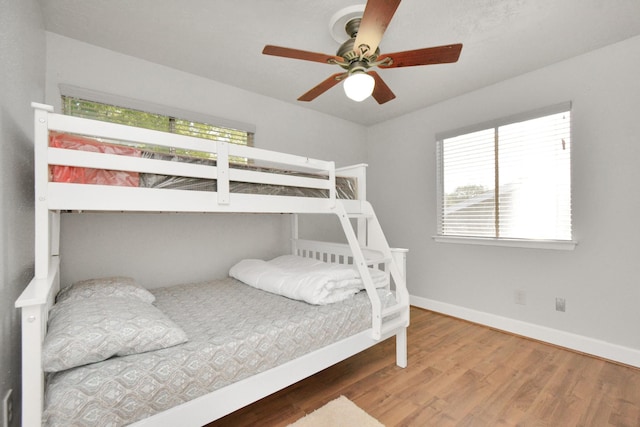 bedroom featuring ceiling fan, hardwood / wood-style floors, and multiple windows