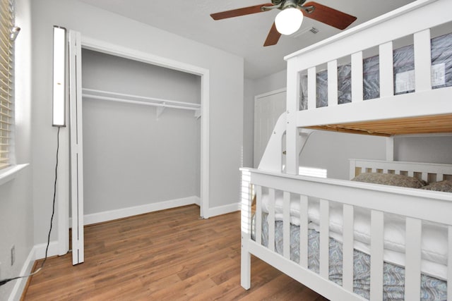 bedroom with ceiling fan, wood-type flooring, and a closet