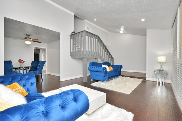 living room featuring dark wood-type flooring, ceiling fan, and a textured ceiling