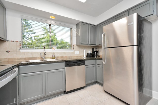 kitchen with sink, gray cabinetry, light tile patterned floors, stainless steel appliances, and decorative backsplash