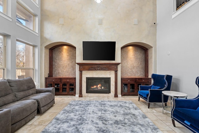 tiled living room with a premium fireplace and a high ceiling