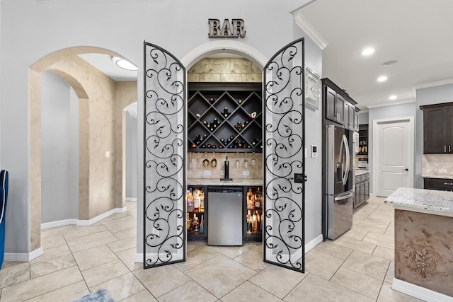 kitchen with light stone countertops, stainless steel fridge with ice dispenser, ornamental molding, fridge, and dark brown cabinets