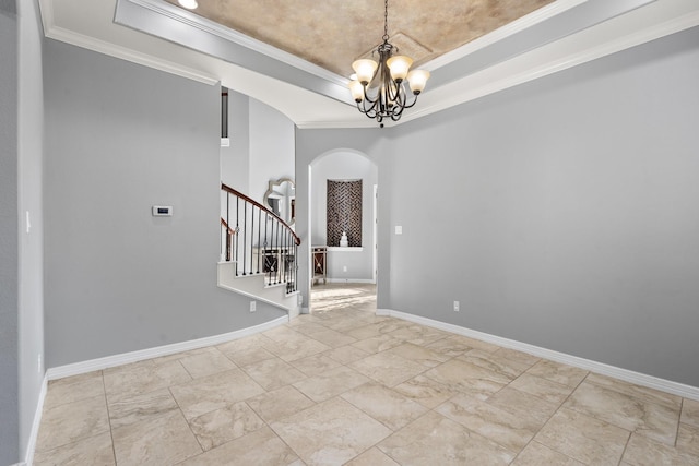 entrance foyer featuring a tray ceiling, ornamental molding, and a chandelier