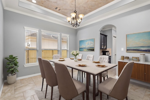 tiled dining space with ornamental molding, a raised ceiling, and a chandelier