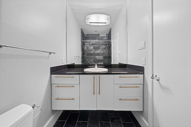 bathroom featuring tiled shower, toilet, and vanity