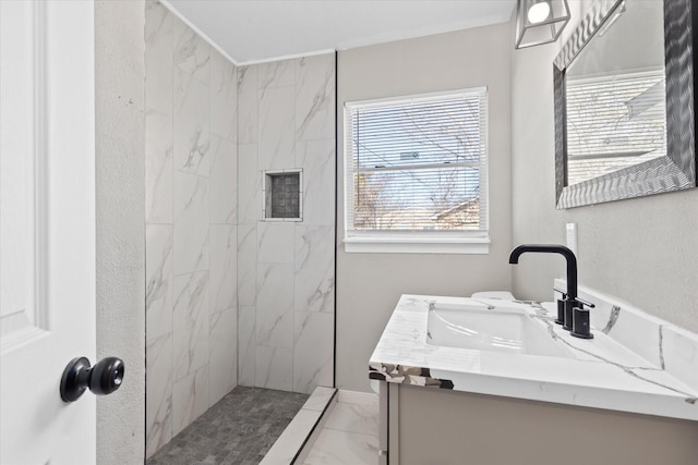 bathroom with tiled shower and vanity