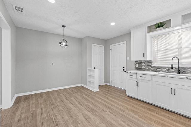 kitchen with decorative light fixtures, sink, white cabinets, and tasteful backsplash