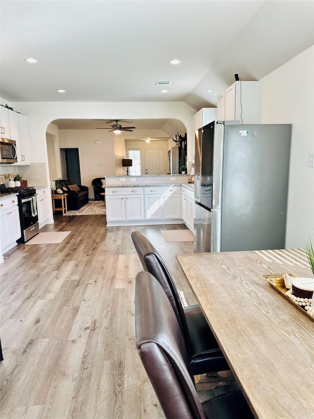 kitchen featuring kitchen peninsula, tasteful backsplash, white cabinetry, and appliances with stainless steel finishes