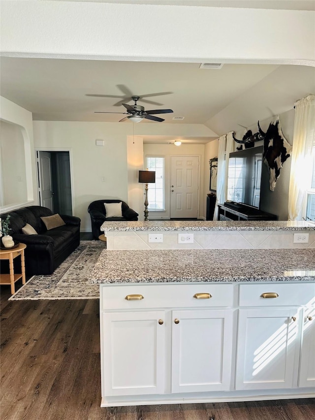 kitchen with white cabinets, ceiling fan, light stone counters, and dark hardwood / wood-style floors