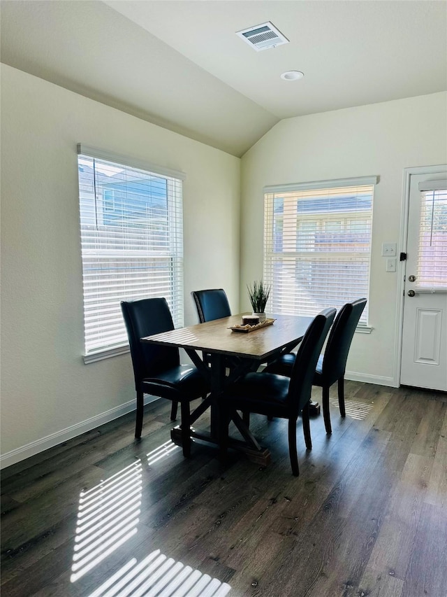 dining area with dark wood-type flooring and vaulted ceiling