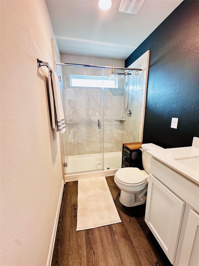 bathroom with vanity, hardwood / wood-style flooring, a shower with door, and toilet