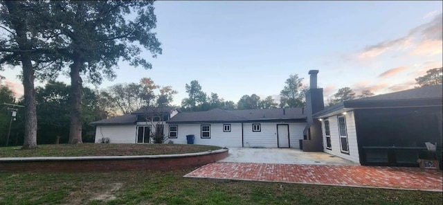 back house at dusk with a patio area