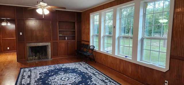 interior space with wood-type flooring, wood walls, and ceiling fan