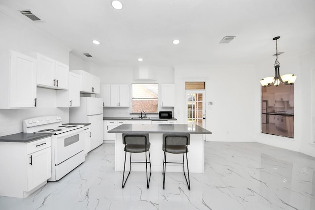 kitchen featuring white cabinetry, white appliances, a center island, and hanging light fixtures