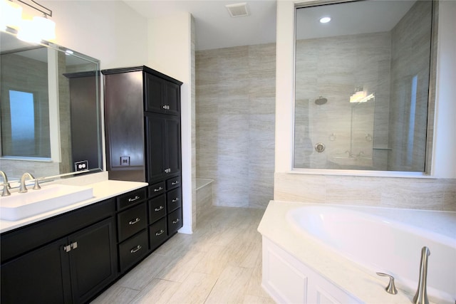 bathroom with vanity, a tub, and tile walls