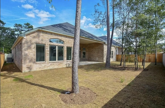 rear view of property featuring a patio area, central AC unit, and a lawn